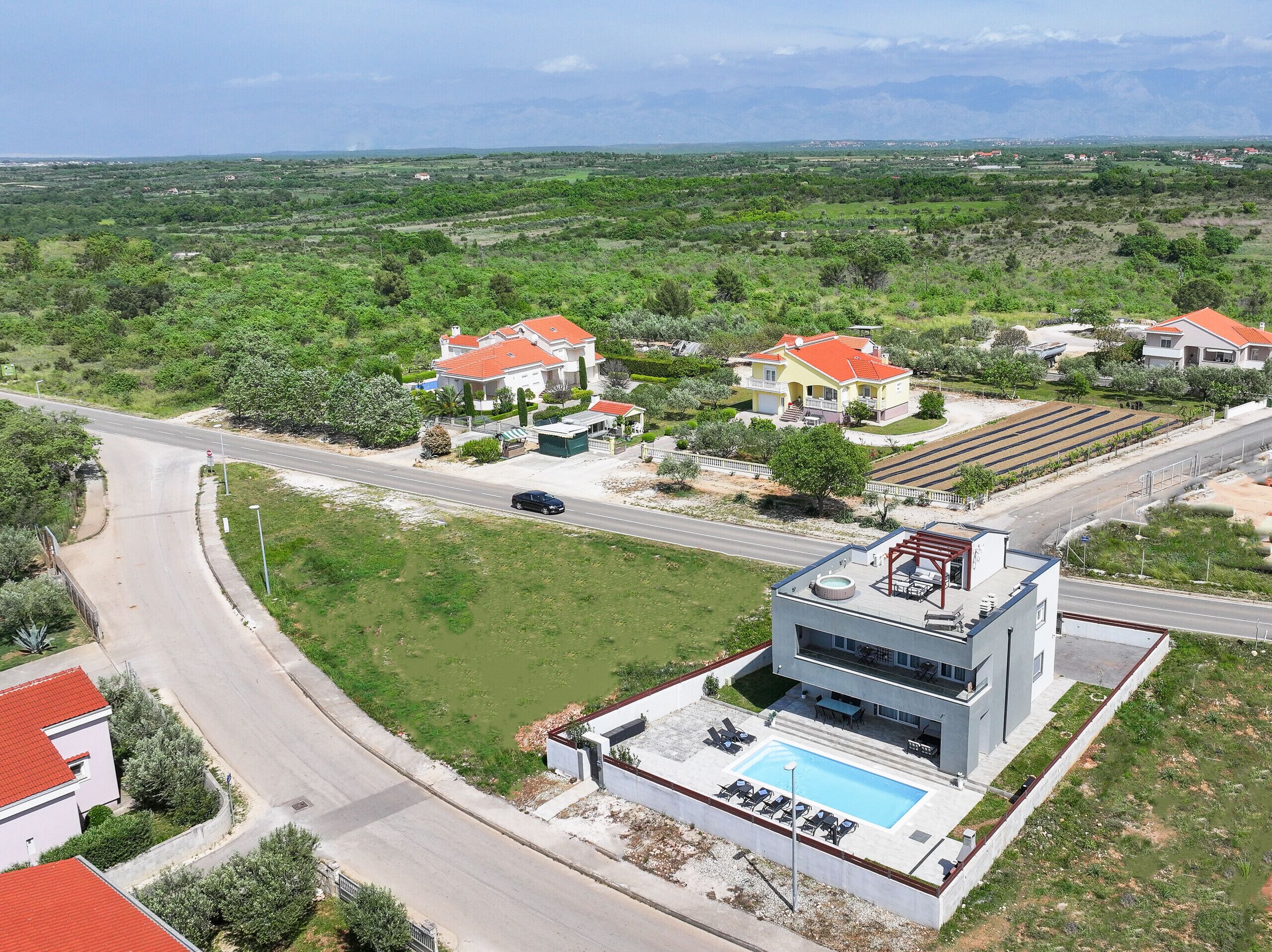 A residential area with houses, a swimming pool, and a road.