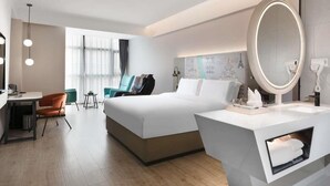 Une chambre d’hôtel moderne équipée d’un grand lit, d’un bureau, d’une chaise, d’une coiffeuse avec un miroir et d’une carte accrochée au mur.