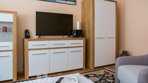 Un salon avec un téléviseur, des haut-parleurs et un canapé.