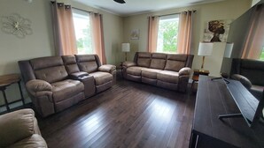 A living room with two reclining sofas, a ceiling fan, and a wooden floor.