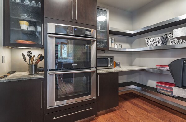 A modern kitchen with stainless steel appliances, wooden cabinets, and a built-in microwave.