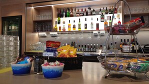 Un espace bar avec un assortiment de bouteilles d’alcool, une sélection de collations et un présentoir à verres.