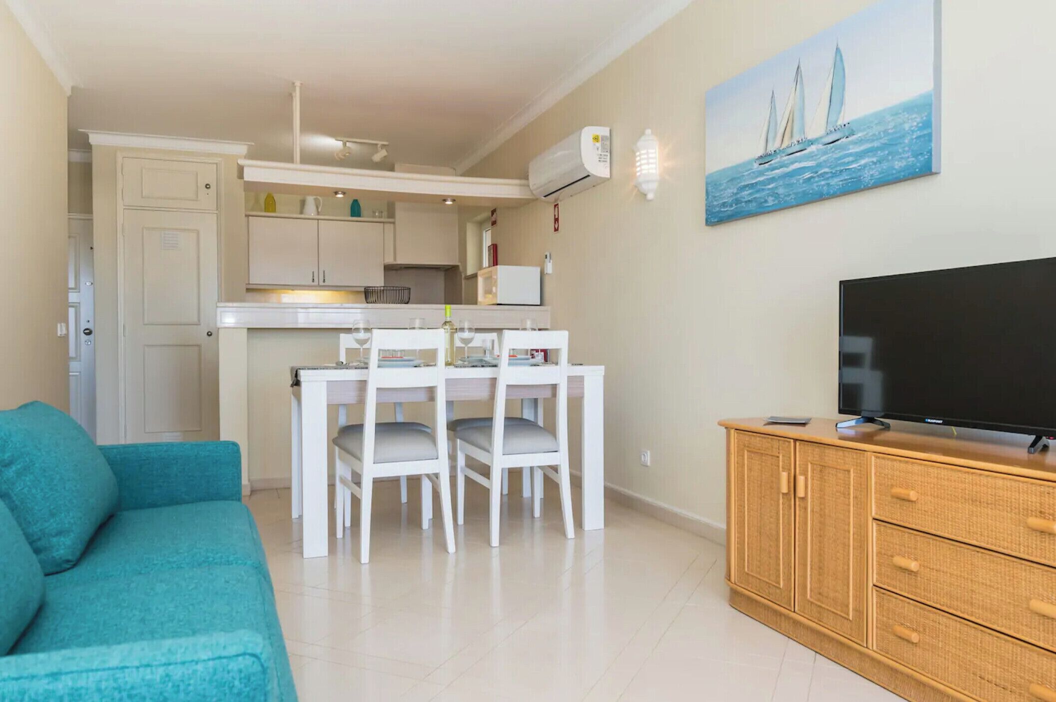A compact living space with a dining area, kitchenette, and a television on a wooden cabinet.