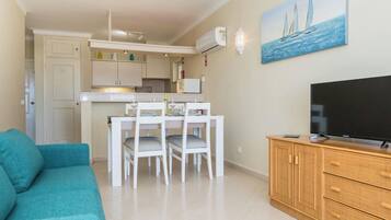 A compact living space with a dining area, kitchenette, and a television on a wooden cabinet.