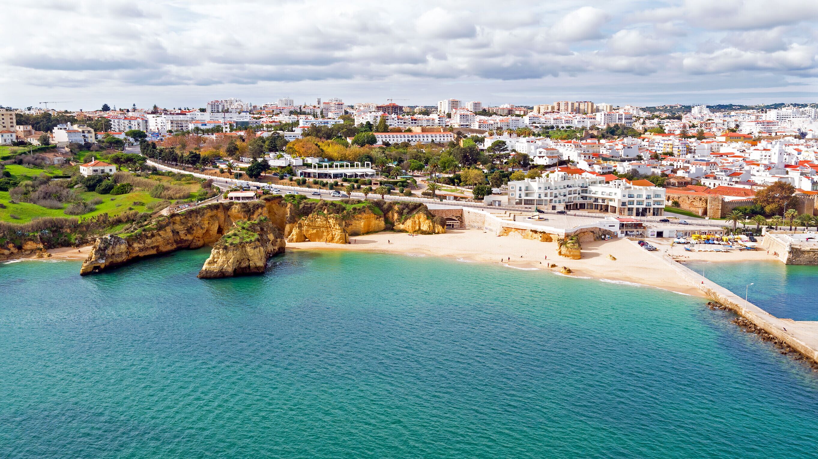 A coastal town with a prominent cliff, a beach, and a road leading through the town.