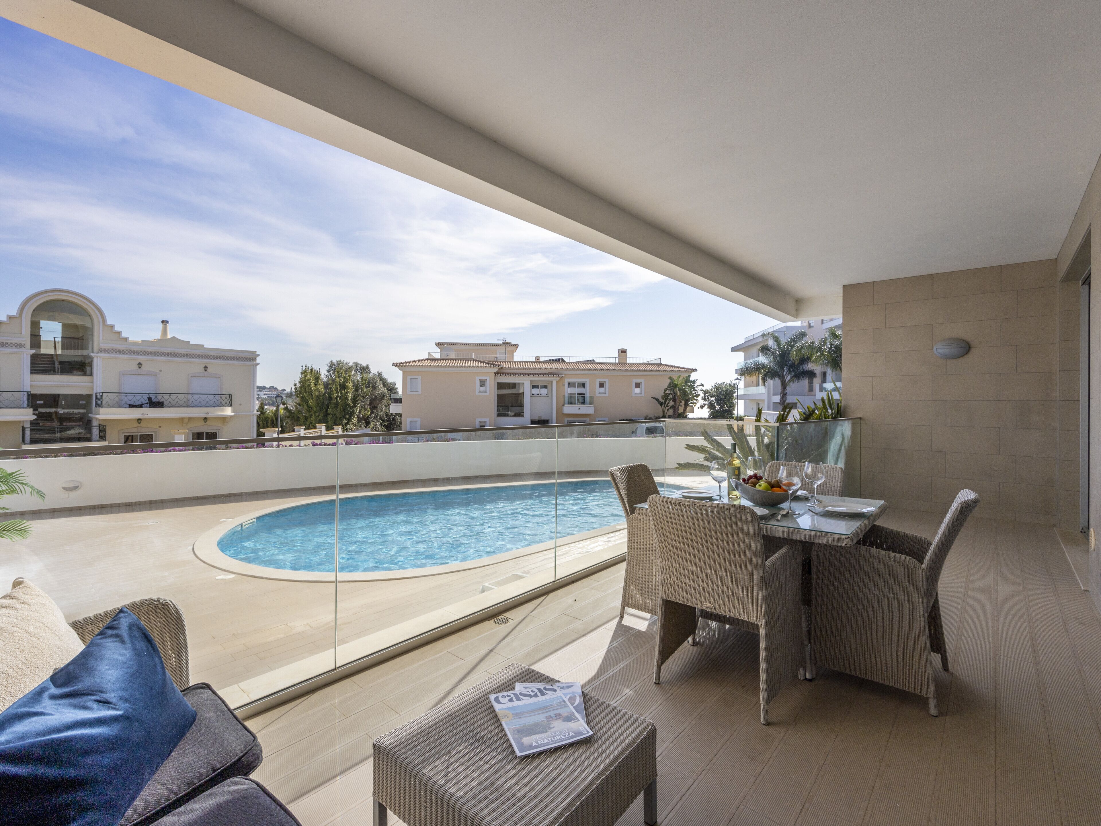A balcony with a pool, wicker furniture, and a table set for dining.