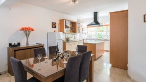 Una cocina moderna con comedor, que incluye una mesa de madera, sillas y un jarrón con flores.