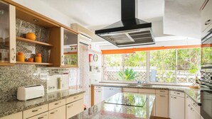 Una cocina moderna con encimeras de granito, horno empotrado y un amplio ventanal con vistas a zonas verdes.
