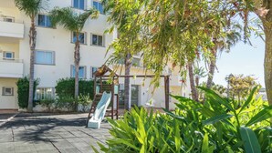 Une cour intérieure agrémentée d’une pergola, de palmiers et d’un bâtiment doté de balcons.