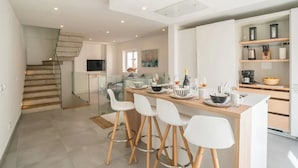A modern kitchen with a central island, bar stools, and a staircase leading to an upper level. - Casa Machado Old Town Lagos (Lagos)