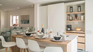 A modern kitchen with a central island, white cabinetry, and a glass partition. - Casa Machado Old Town Lagos (Lagos)