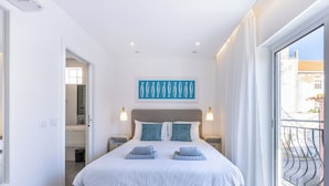 A modern bedroom with a large bed, two bedside tables, a ceiling light, and a view of the outside. - Casa Machado Old Town Lagos (Lagos)