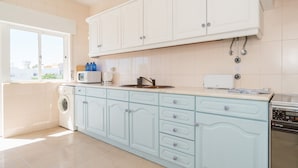 A modern kitchen with white cabinets, a built-in washing machine, and a dishwasher. - Sunny Seaside Escape (Lagos)