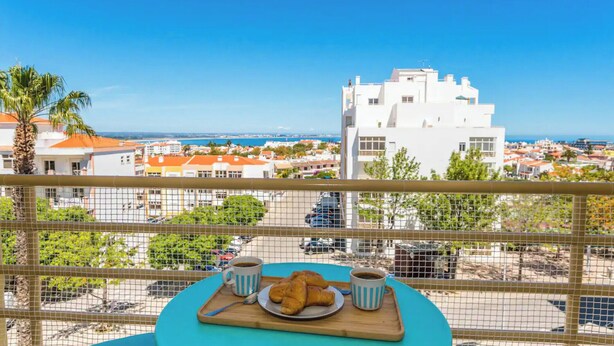 A balcony with a table set for breakfast, overlooking a coastal cityscape. - Sunny Seaside Escape (Lagos)