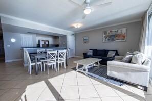 A modern living room with a dining area, a sofa, and a ceiling fan.