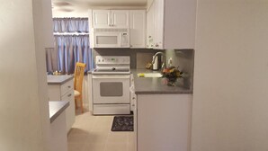 A compact kitchen with white cabinets, a microwave, an oven, and a sink. -  Downtown Safety Harbor 2 Bed 1 Bath Pool Home, 20 minutes from Clearwater beach (Safety Harbor)