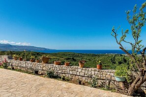A stone wall with potted plants and a view of the sea.