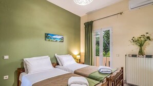 Hotellihuone, jossa on kaksi sänkyä, seinällä taulu, ikkunassa verhot ja huoneessa patteri.