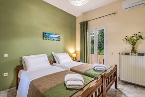 Camera d'albergo con due letti, un quadro appeso al muro, una finestra con tende e un termosifone.