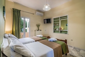 A hotel room with two beds, a TV, a window with a view, and a shelf with books and decorative items.