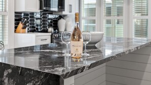 A kitchen with a marble countertop, a wine bottle, and two wine glasses. - Cozy WaterColor Condo - 3rd Floor Unit, Steps to Beach Club & Seaside, Bikes! (Santa Rosa Beach)