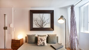 Une chambre à coucher avec un lit, une table de chevet, une lampe et un tableau encadré au mur.