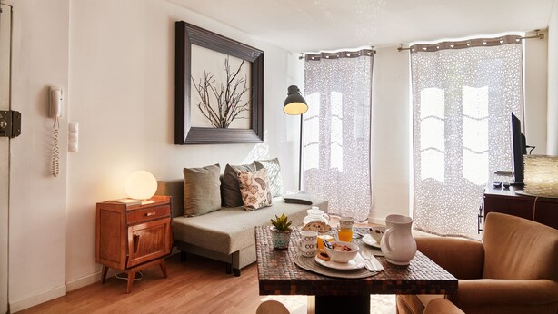 Un salon confortable avec un canapé, une table basse sur laquelle sont disposés des éléments pour le petit-déjeuner et une lampe.