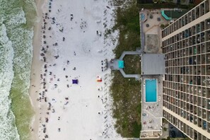 Ein Luftbild einer Strandlandschaft mit einem angrenzenden Hotelgebäude.