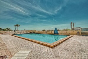 A swimming pool with a tiled deck, a lifeguard stand, and palm trees in the background. - The Oyster | Beachfront Condo (Destin)