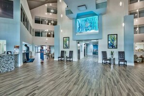 A spacious lobby with a high ceiling, a reception desk, and seating areas. - The Oyster | Beachfront Condo (Destin)