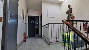 Un passadís amb un extintor, una porta amb la inscripció "Cafeteria" i una escala amb barana.