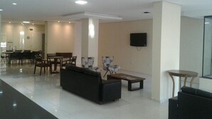 A modern living room with a sofa, armchairs, a coffee table, and a TV mounted on the wall. - Hotel Recanto Vip (Araripina)