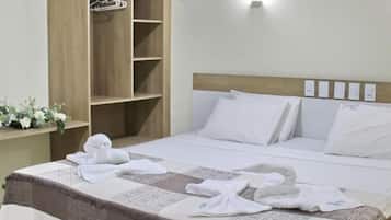 Quarto de hotel com uma cama, guarda-roupa de madeira e luminária fixada na parede.