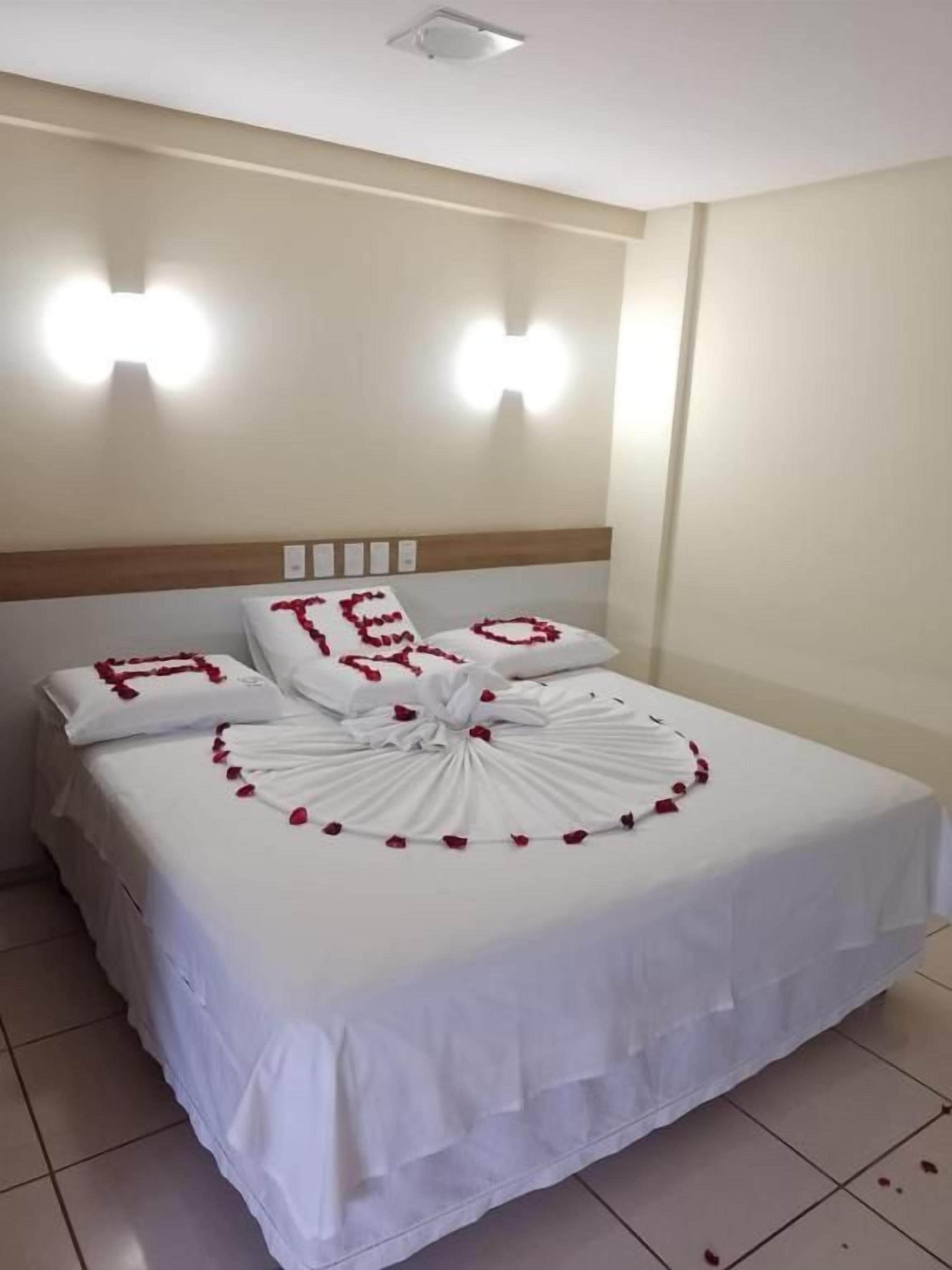 Een hotelkamer met een net opgemaakt bed, een hoofdeinde met lichtschakelaars en wandlampen.