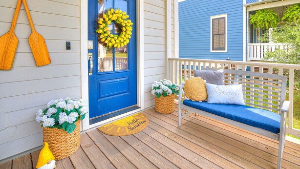 A porch with a blue door, a bench, and a wreath.