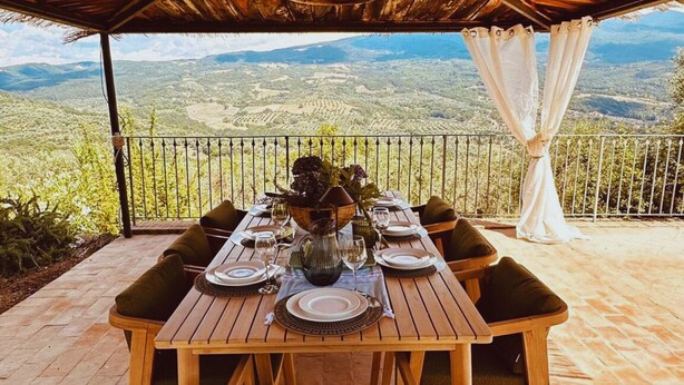 A dining table set for four with a view of a mountainous landscape.