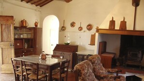 A traditional living room with a fireplace, wooden furniture, and a dining area. - Casalunga, beautiful farmhouse with swimming pool and garden (Buonconvento)