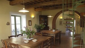 A dining area with wooden tables and chairs, a potted plant, and a staircase with a green railing. - Case Belle, beautiful villa in the heart of the Val d'Orcia with 12 sleeping accommodations (Sarteano)