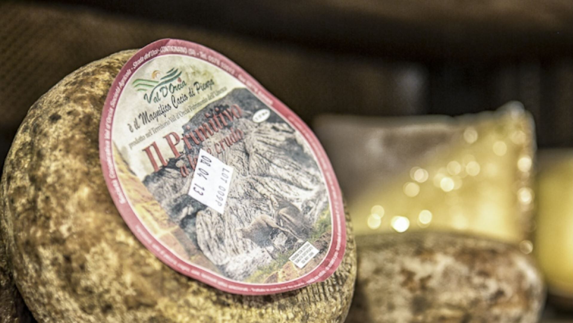 A package of Il Primitivo cheese on a wooden surface.