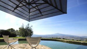 A poolside area with two chairs and a large umbrella, overlooking a mountain range. - Case Belle, beautiful villa in the heart of the Val d'Orcia with 12 sleeping accommodations (Sarteano)