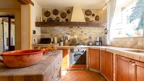 A rustic kitchen with stone walls, wooden cabinets, and a large oven. - Villa La Felce, a typical Tuscan farmhouse surrounded by nature (Cetona)