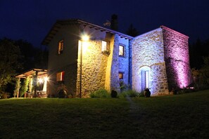 A stone building with a wooden structure adjacent to it, both illuminated by artificial lighting. - Villa La Felce, a typical Tuscan farmhouse surrounded by nature (Cetona)