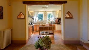 A kitchen with wooden cabinets, a central island, and a view of the outdoors through large windows. - Villa La Felce, a typical Tuscan farmhouse surrounded by nature (Cetona)