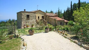 A stone building with a gravel driveway and potted plants. - Villa La Felce, a typical Tuscan farmhouse surrounded by nature (Cetona)