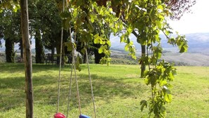 A grassy outdoor area with a swing set and a view of rolling hills in the background. - Splendid villa with view in Castiglioncello sul Trinoro (Castiglioncello sul Trinoro - Sarte)