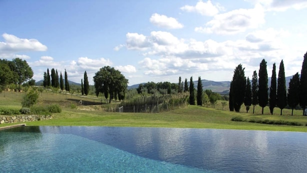A clear blue pool surrounded by a grassy landscape with trees and a stone wall. - Splendid villa with view in Castiglioncello sul Trinoro (Castiglioncello sul Trinoro - Sarte)