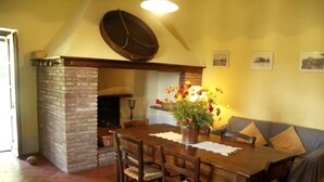 A dining area with a brick fireplace, wooden table, and chairs. - Splendid villa with view in Castiglioncello sul Trinoro (Castiglioncello sul Trinoro - Sarte)
