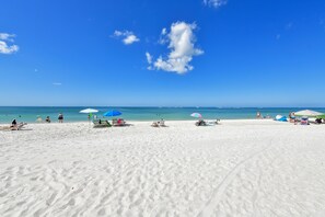 A beach with white sand, clear blue sky, and a few umbrellas. - Bermuda Bay #4 Gorgeous unit, view of the beach off balcony, heated pool and spa (Bradenton Beach)