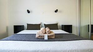 Ein ordentlich bezogenes Bett mit Etikett, zwei Kissen und einem Nachttisch.