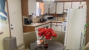 Un comedor con una mesa redonda, cuatro sillas y una lámpara de araña.